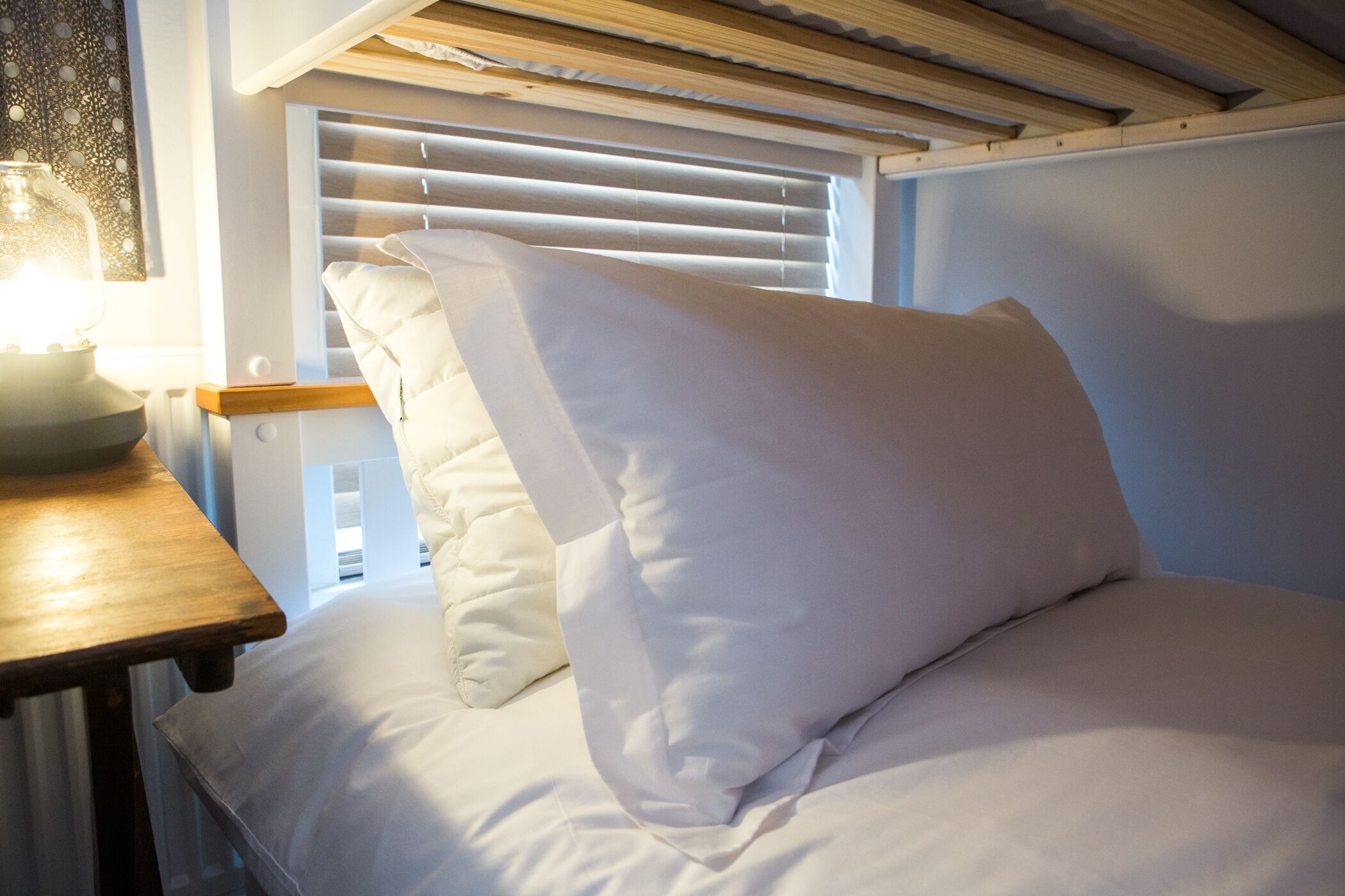 Ein Bett mit weißer Bettwäsche und einem Holzkopfteil.