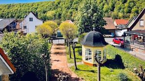 A residential area with houses, a gazebo, and a red car parked on the street. - Pure enjoyment of nature on the Werra Valley Cycle Path (Ebenshausen)