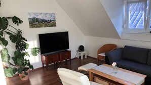 A living room with a TV, a sofa, a chair, a coffee table, and a potted plant. - Pure enjoyment of nature on the Werra Valley Cycle Path (Ebenshausen)