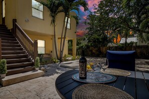 A patio area with a table set for two, a bottle of wine, and a blue chair. - Entire Home in City-Place, Convention Center (West Palm Beach)