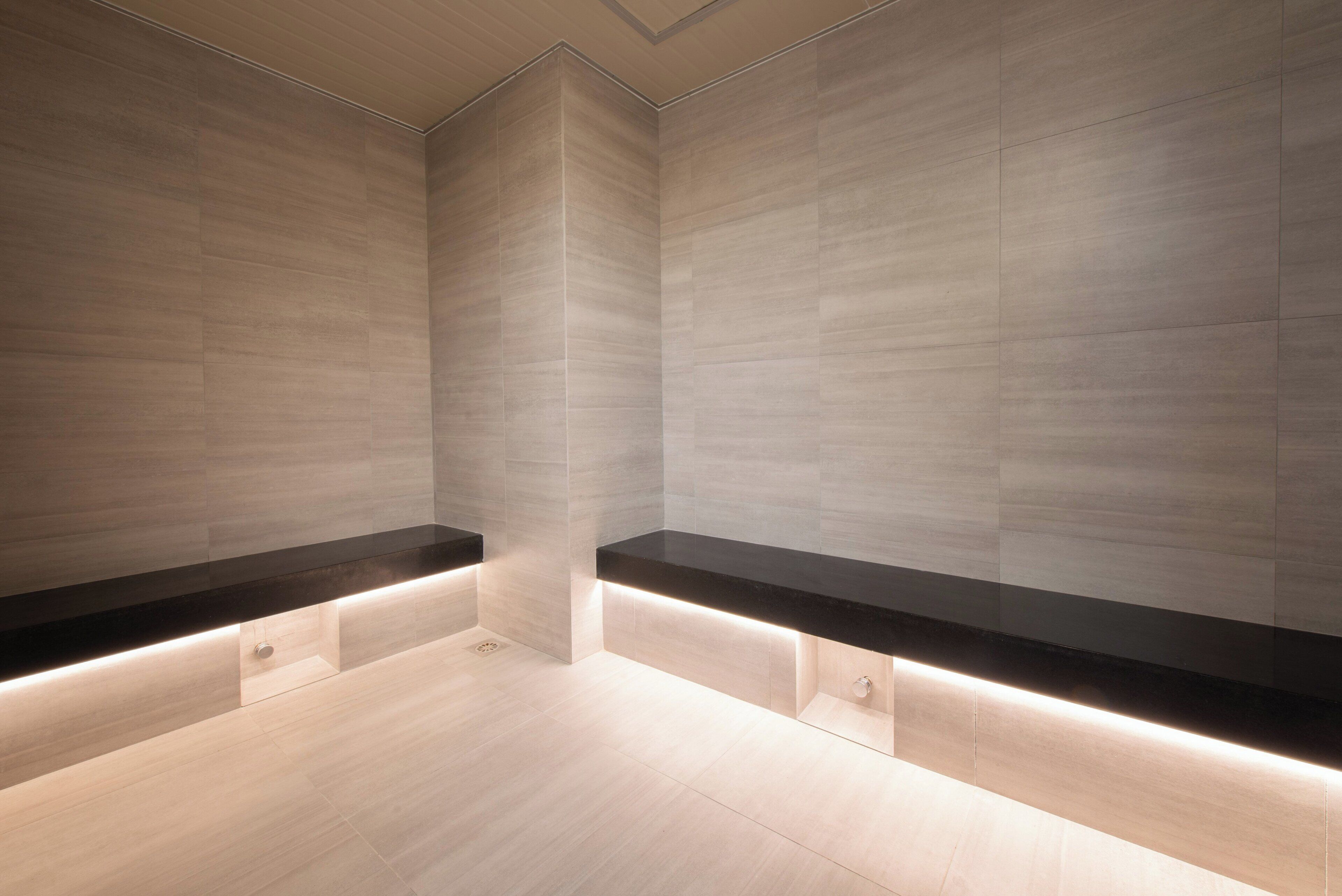 A modern bathroom with a minimalist design, featuring light-colored tiles and black countertops.