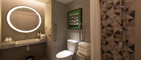 A modern bathroom with a round mirror, toilet, sink, and shower.