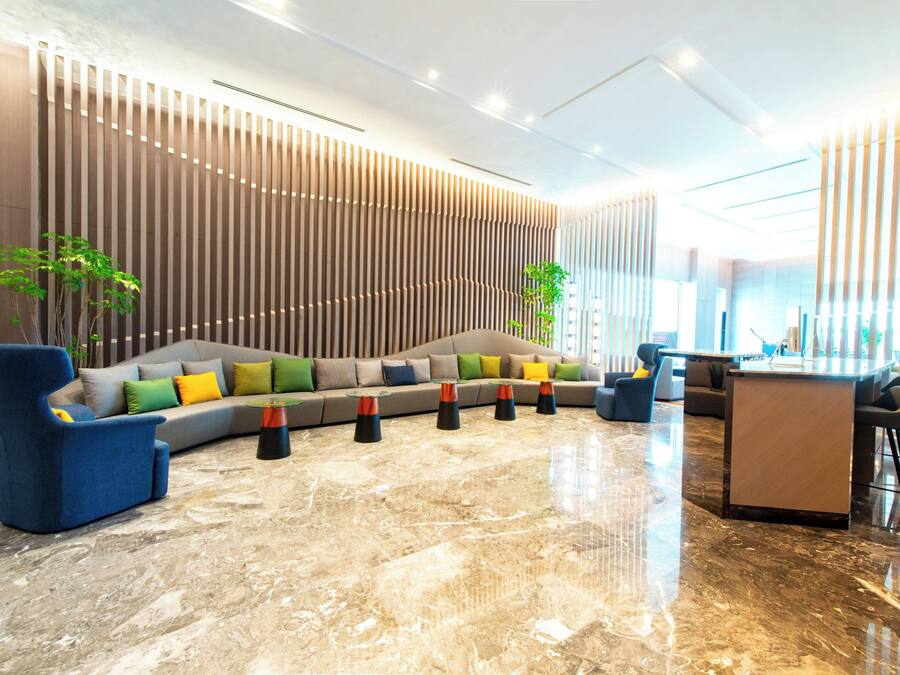 A modern lobby with a sectional sofa, a blue armchair, and a glass-top coffee table.
