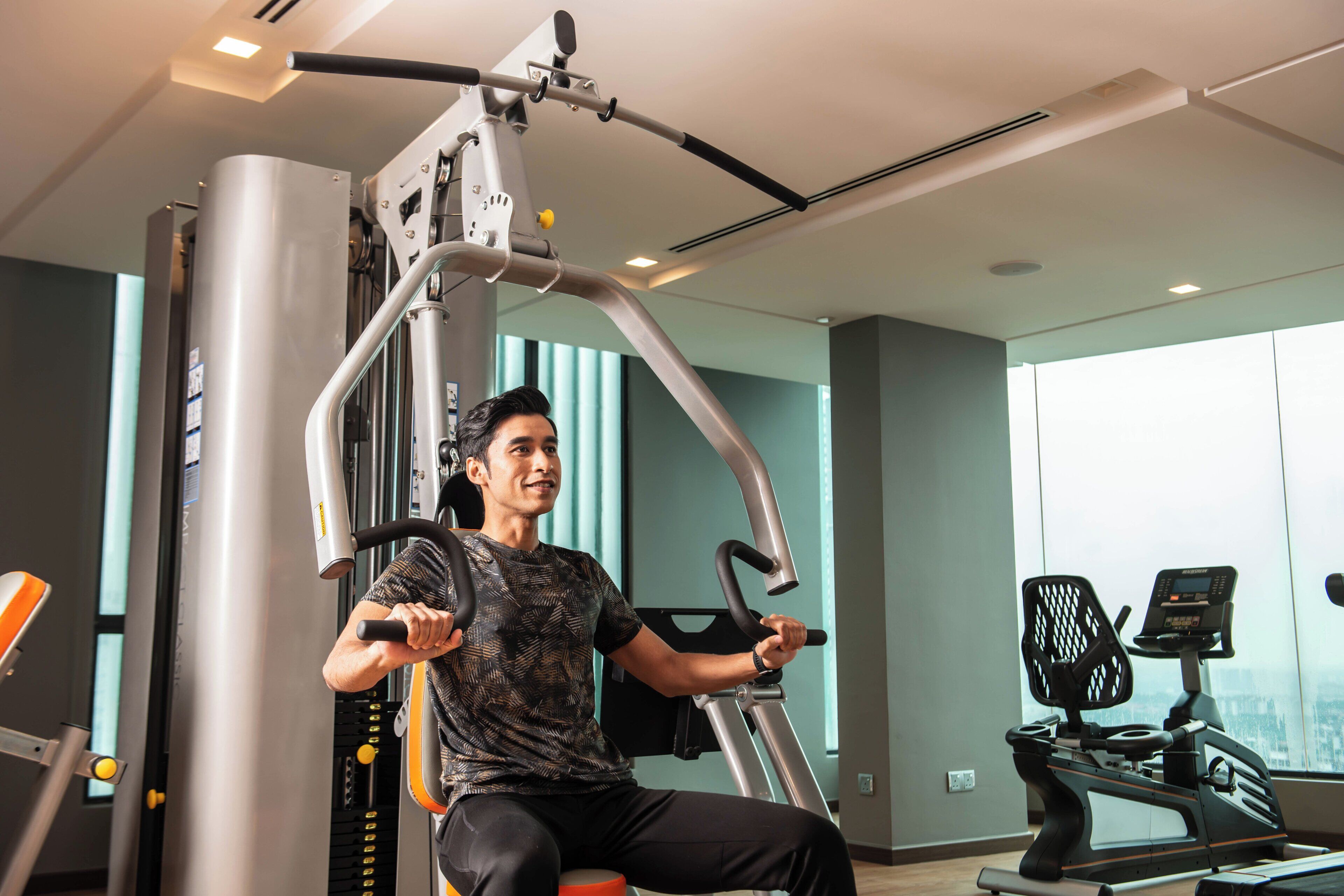 A gym with exercise equipment, a treadmill, and large windows.