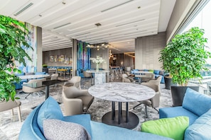 Un área de descanso moderna con asientos, una mesa central y detalles decorativos.
