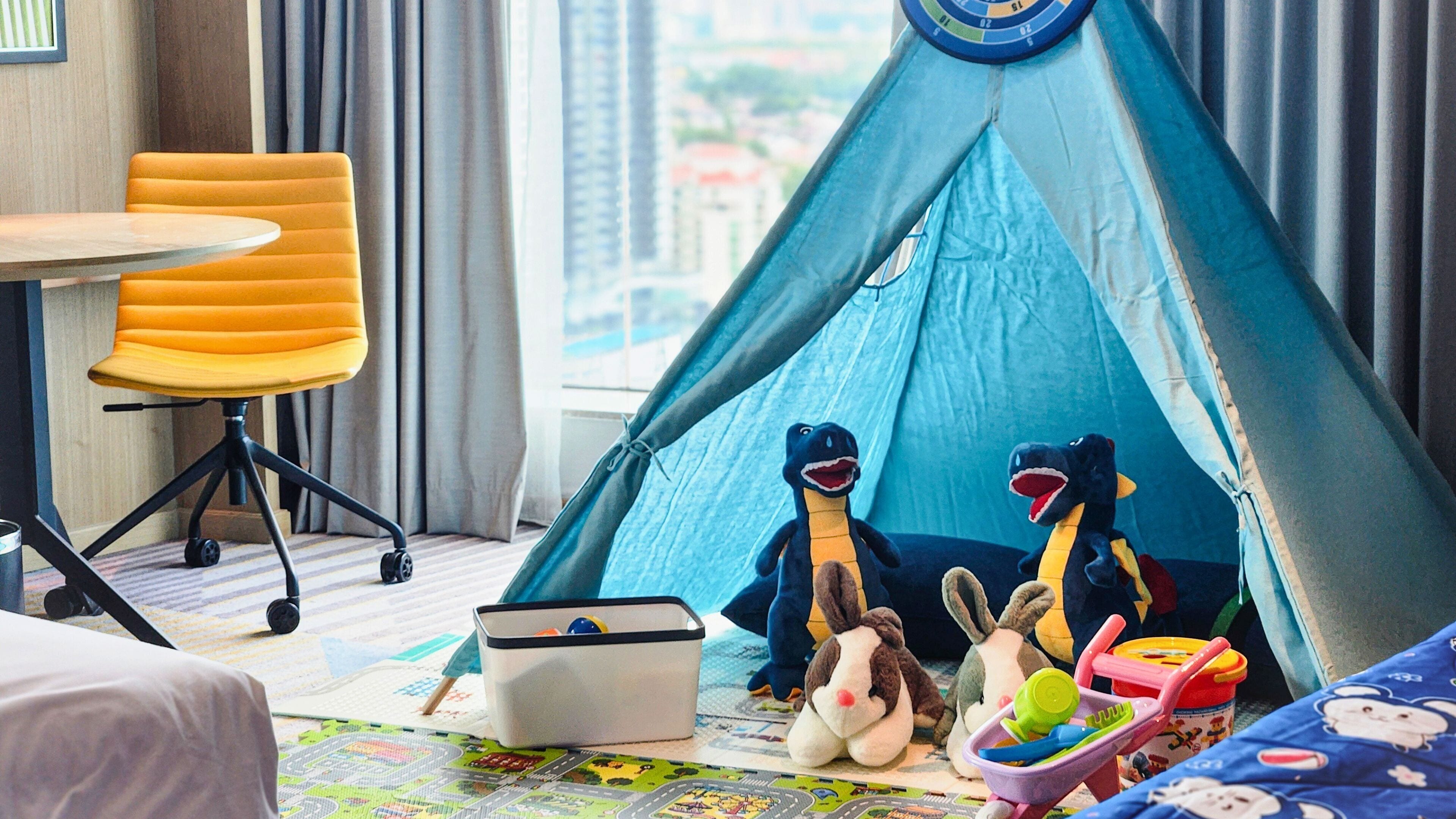 Ein Zimmer mit einem blauen Zelt, einem gelben Stuhl und verschiedenen Spielzeugen.