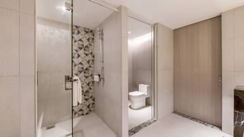 A modern bathroom with a glass-enclosed shower, a toilet, and a marble-tiled floor.
