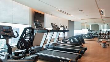 A modern gym with multiple treadmills, a rowing machine, and a weight rack.