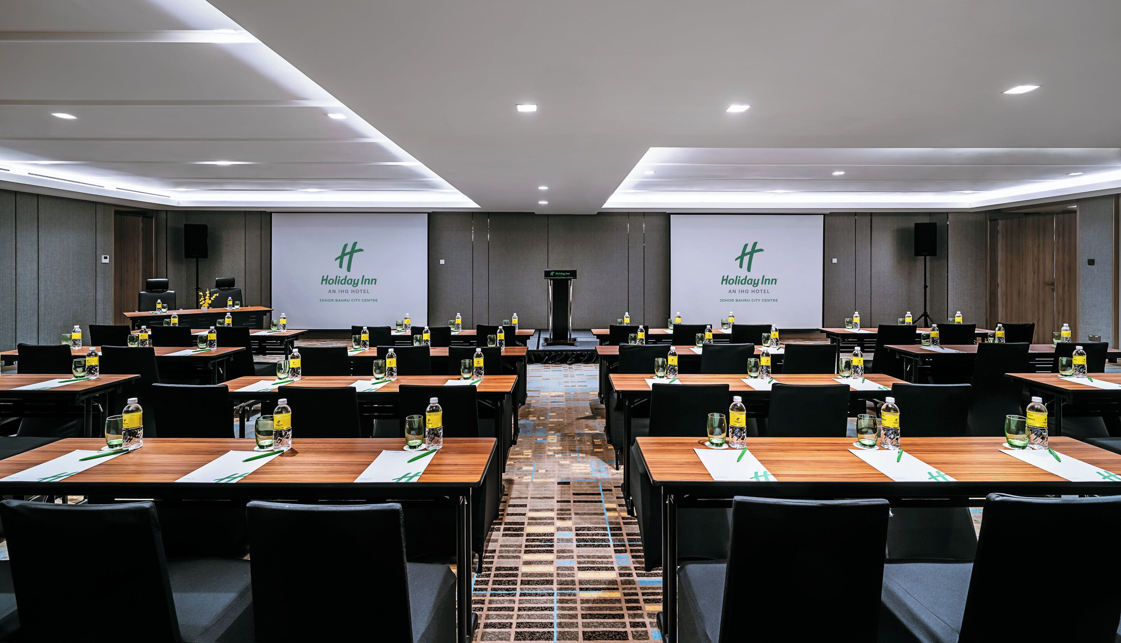 A conference room with multiple tables, chairs, and a podium.
