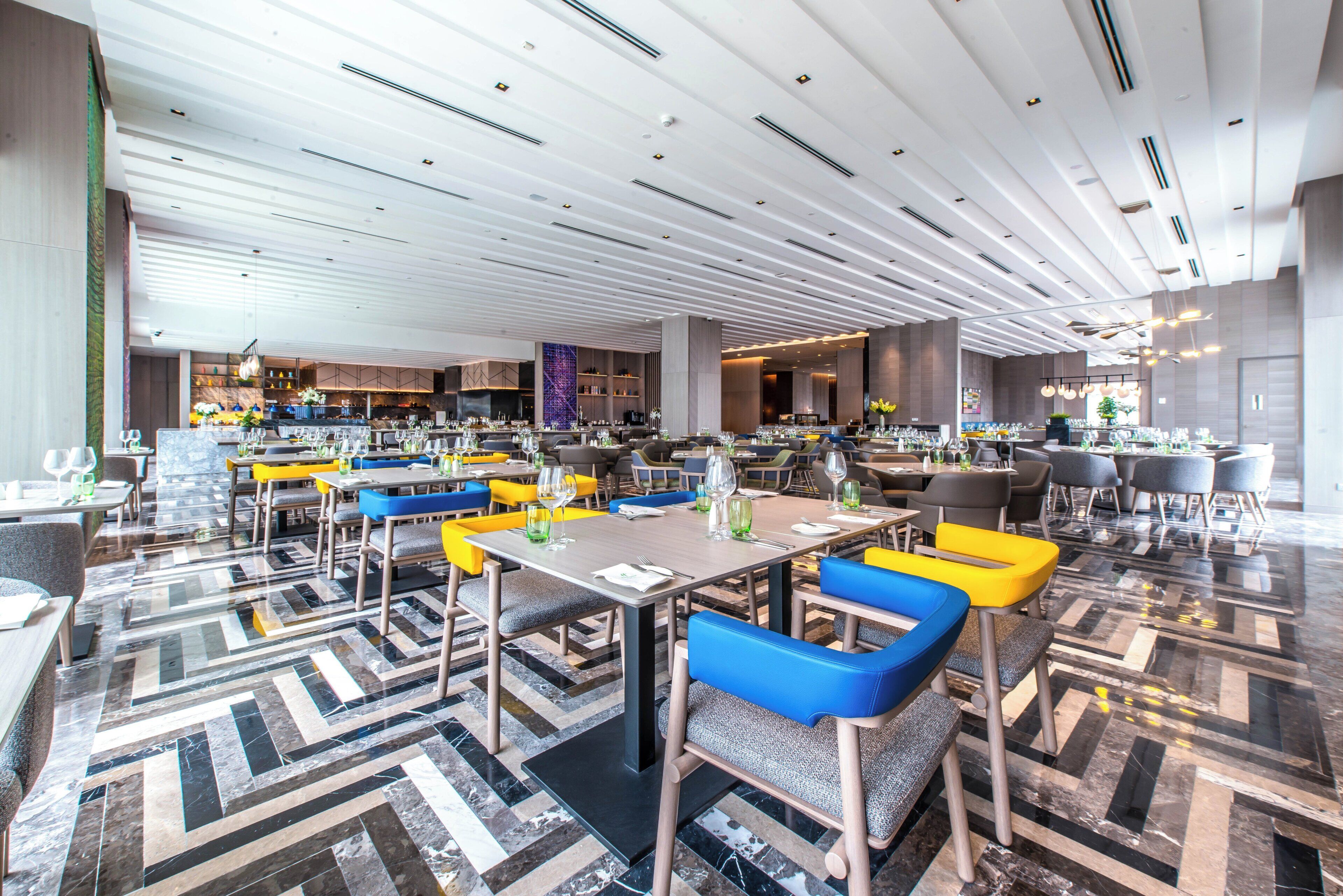 A spacious restaurant with modern decor, featuring a mix of seating arrangements and a patterned floor.