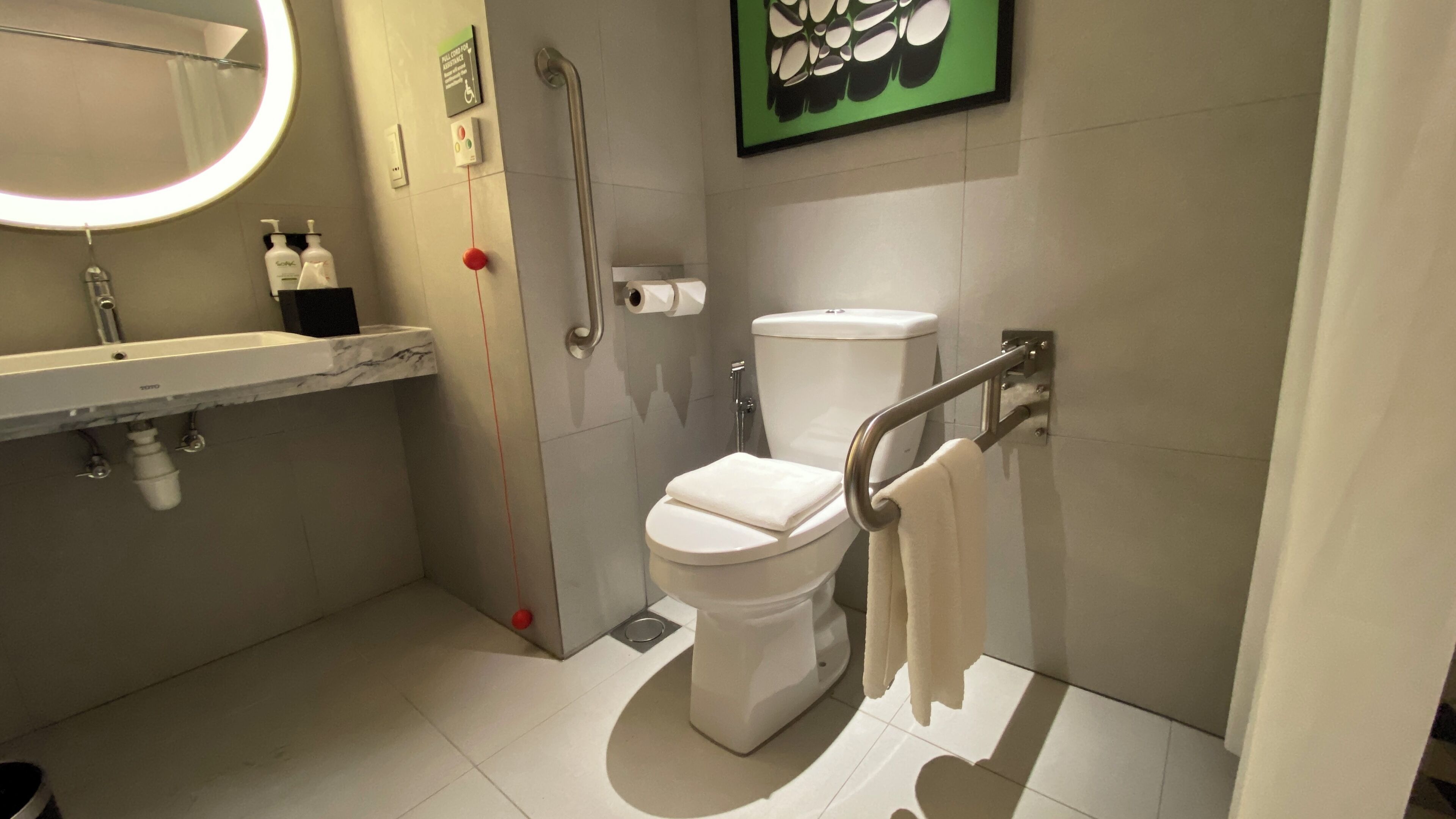 A modern bathroom with a toilet, a hand dryer, a sink, and a mirror.