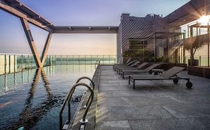 A rooftop pool area with lounge chairs and a glass railing overlooking a body of water. - Holiday Inn Johor Bahru City Centre by IHG (Johor Bahru)