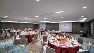 A banquet hall with round tables set for a formal event, featuring a consistent layout and neutral decor.