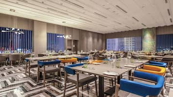 A modern dining area with multiple tables and chairs, a patterned floor, and a ceiling with recessed lighting.
