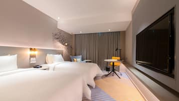 A modern hotel room with a large bed, a small table, a chair, a TV, and a large window.