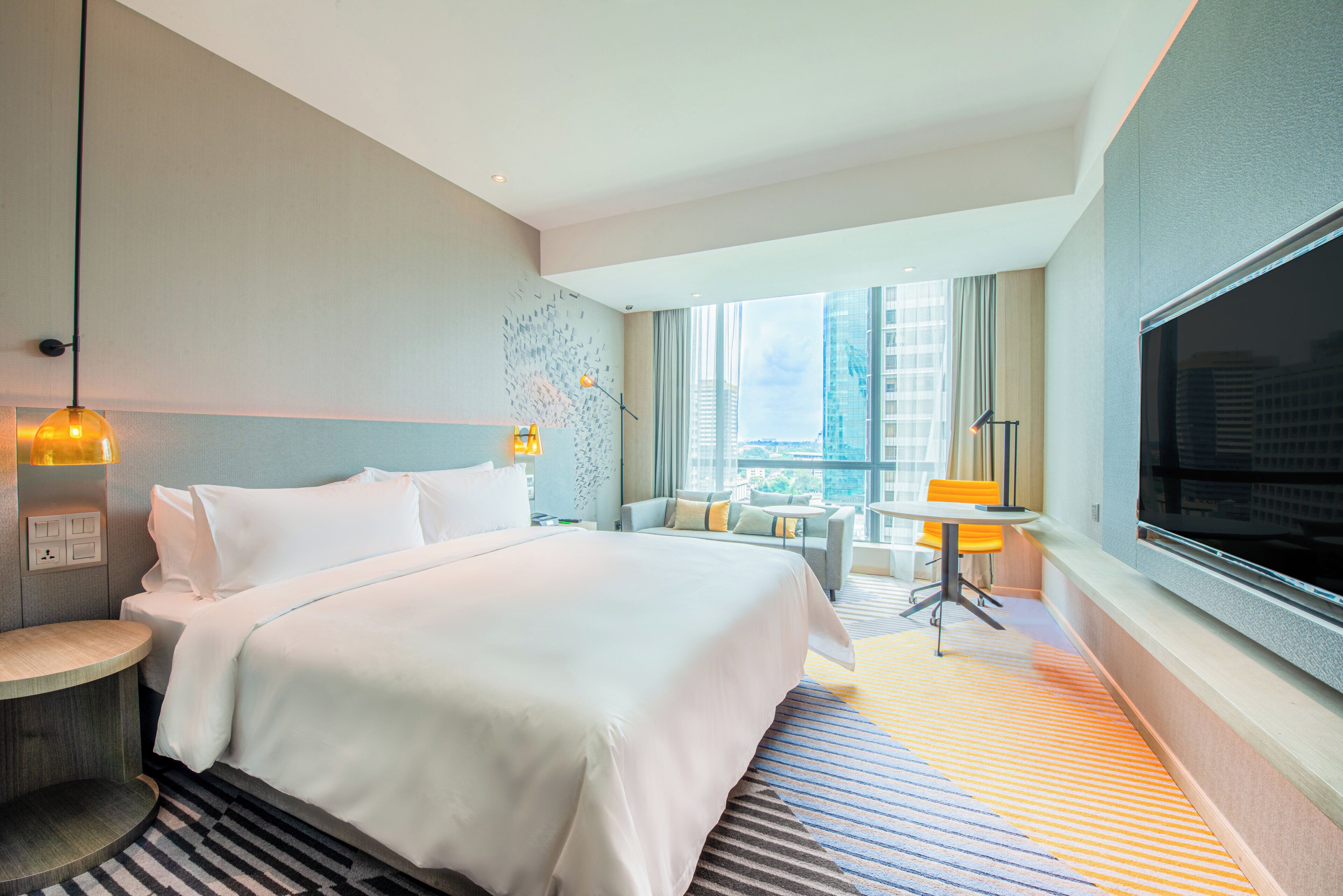 A hotel room with a large bed, a desk, a chair, and a TV.