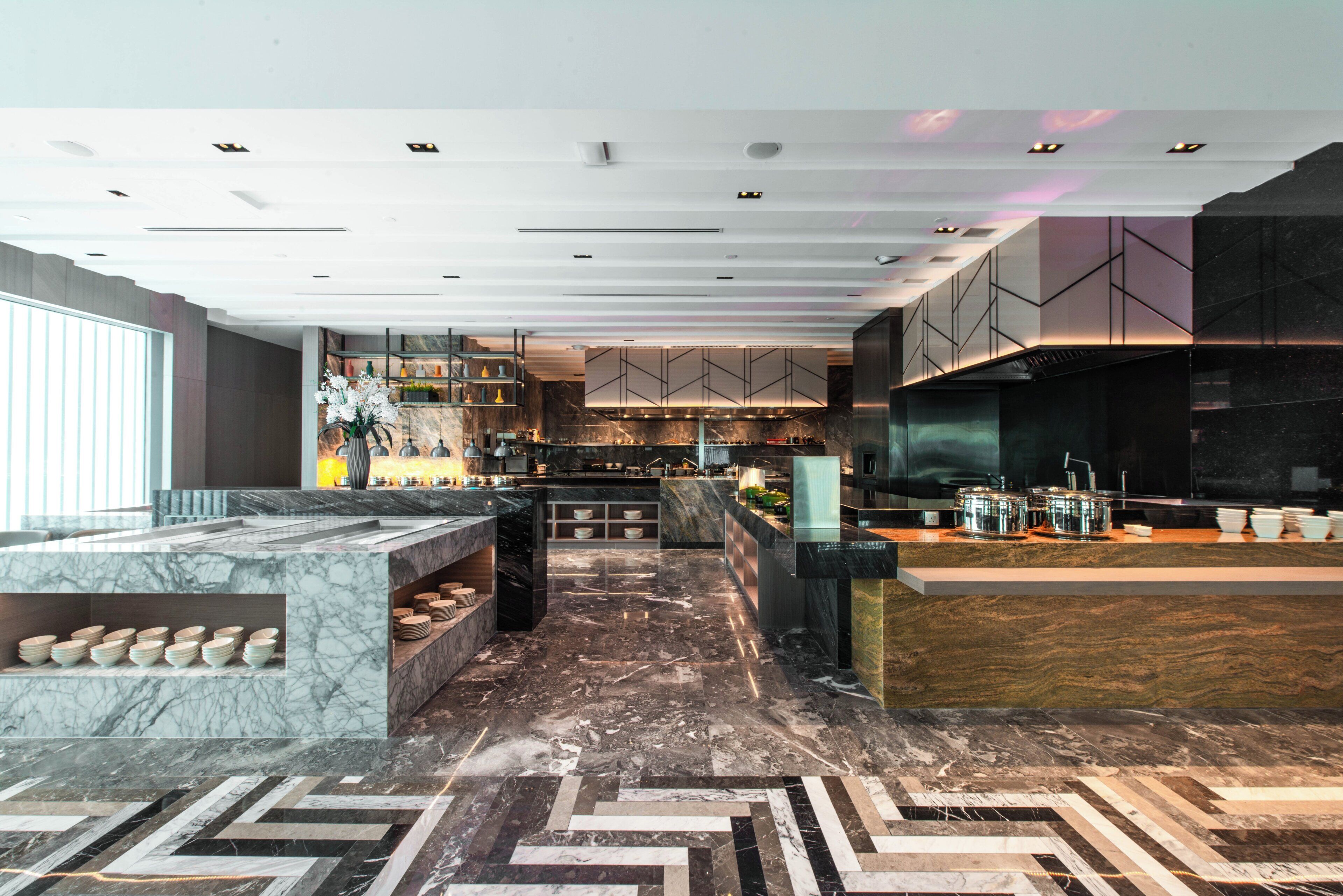 Une cuisine moderne dotée de plans de travail en marbre, d’un îlot central et d’un sol décoré d’un motif en chevrons.