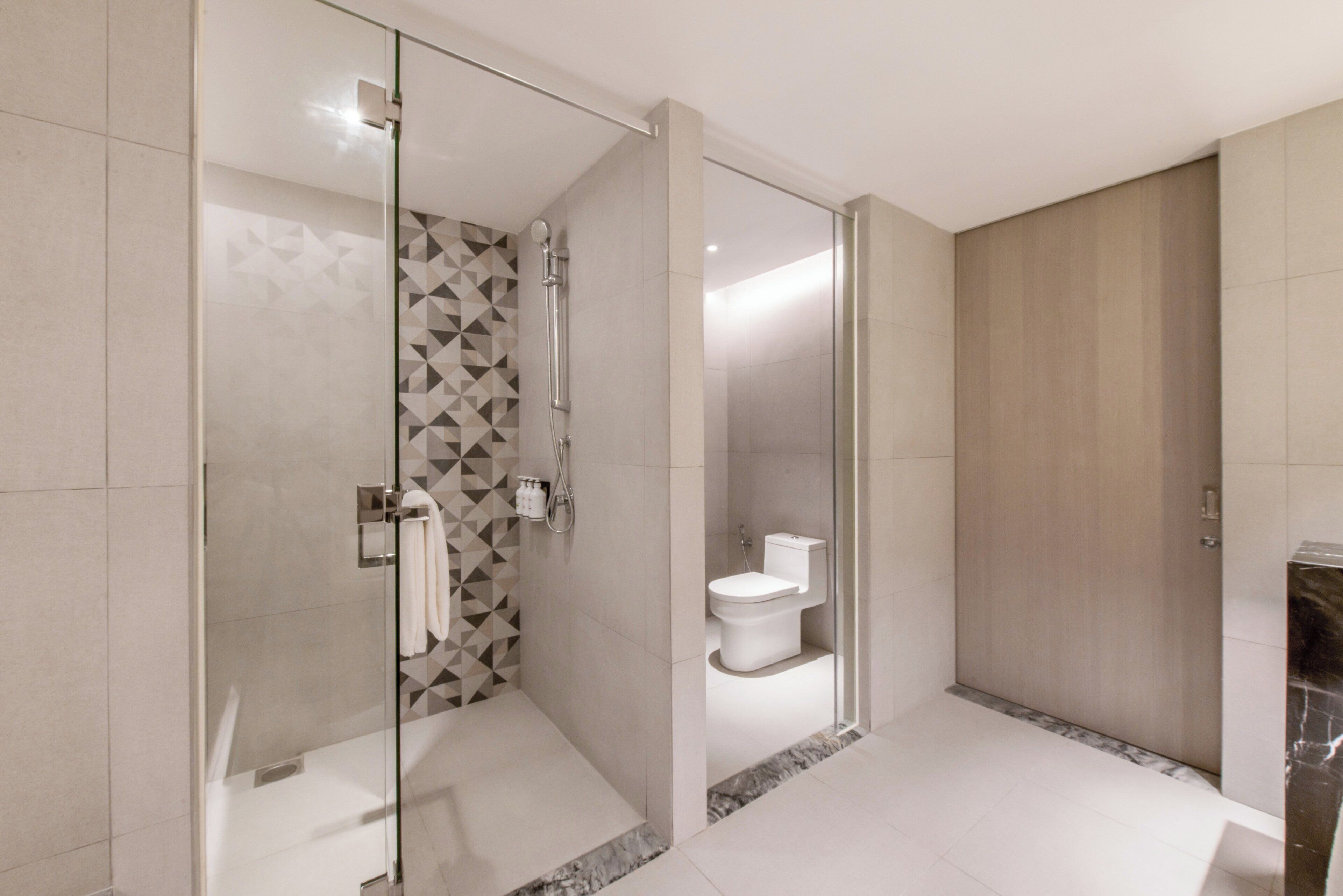 Ein modernes Badezimmer mit Duschkabine aus Glas, Toilette und Marmorboden.