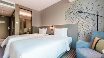 A hotel room with two beds, a seating area, and a decorative wall.