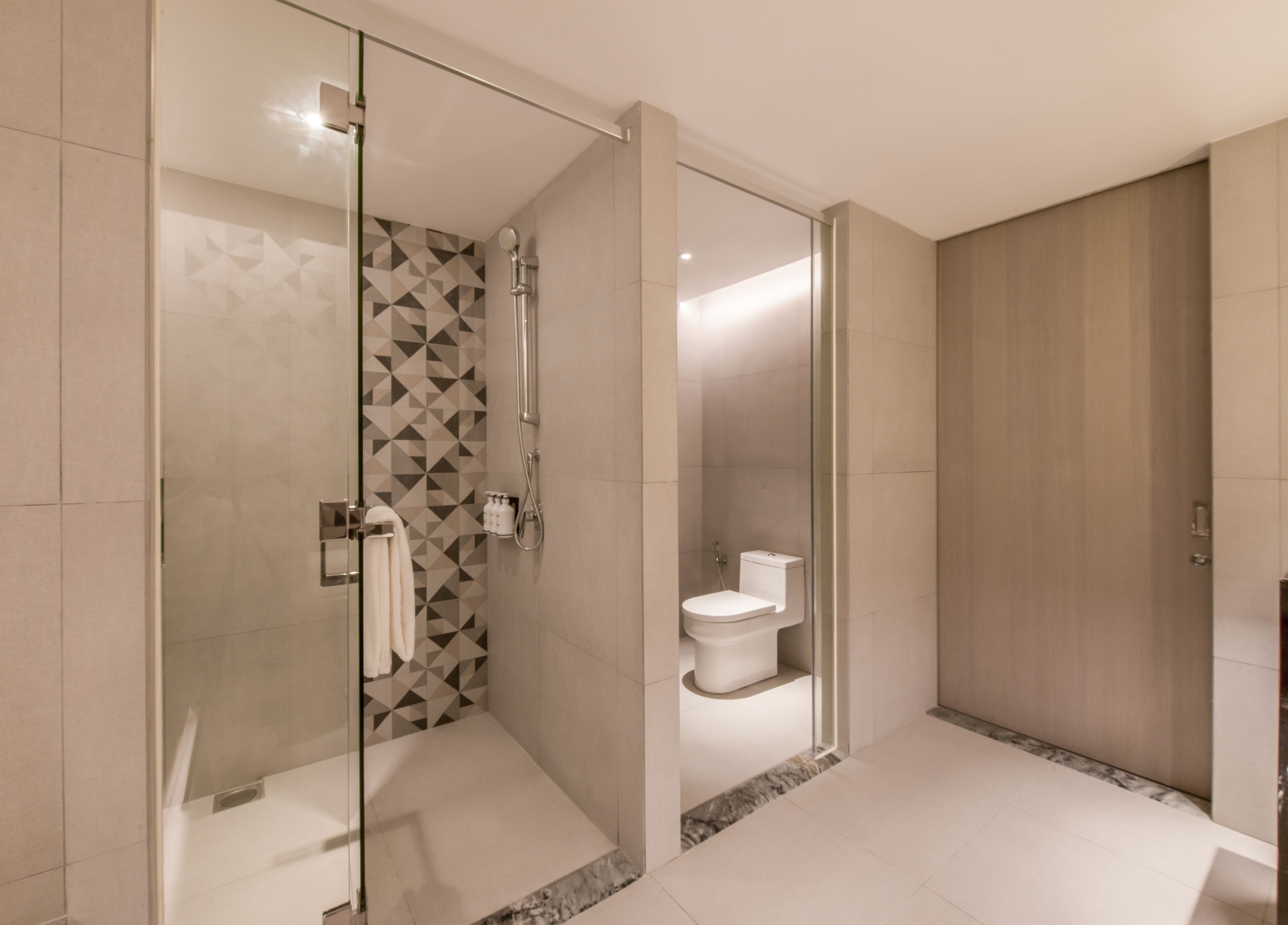 A modern bathroom with a glass-enclosed shower, a toilet, and a walk-in shower area.