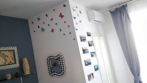 A room with a blue wall, a decorative mirror, butterfly wall decals, and a series of framed pictures. - Room-versomare - Room Scirocco - Cis Ba (Polignano a Mare)