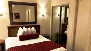Una habitación de hotel con una cama grande, un espejo encima y una puerta corredera que da a un baño.