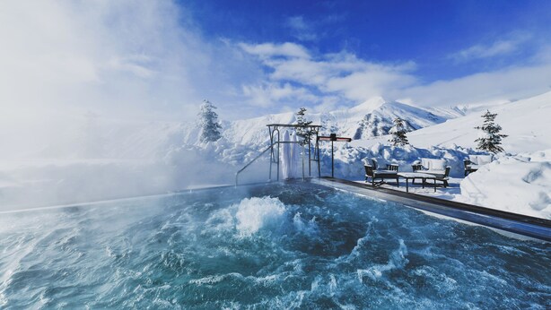 A snow-covered outdoor area with a heated pool, benches, and a metal structure. - Gudauri Lodge (GUDAURI)
