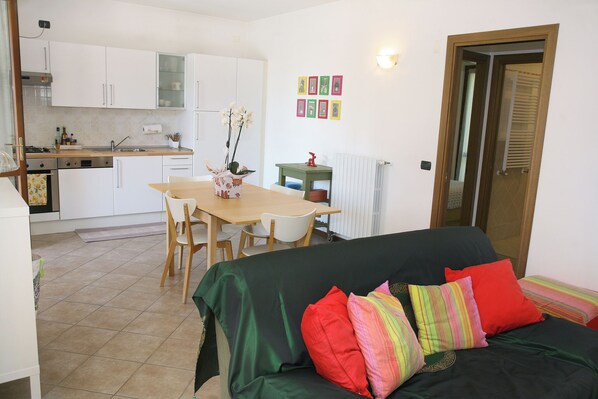 A compact living space with a kitchenette, a dining area, and a sofa with colorful cushions.