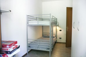 Ein Mehrbettzimmer mit einer kleinen Tafel, auf der Gesellschaftsspiele liegen, einer Tür und einer Lampe.