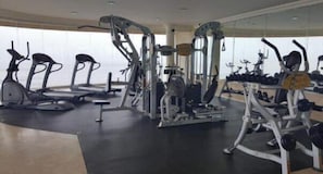 Une salle de sport équipée de divers appareils d’exercice, notamment des tapis de course, des vélos d’appartement et des appareils de musculation.