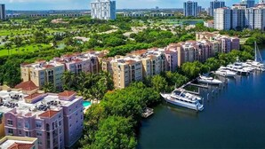A marina with boats docked, surrounded by multi-story residential buildings with balconies.