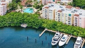 A high-rise hotel with multiple balconies, a swimming pool, and a marina with boats.