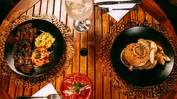 A wooden table with two plates of food, a glass of drink, and cutlery.