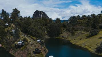 A lakeside property with a large rock formation, boats, and a dock.