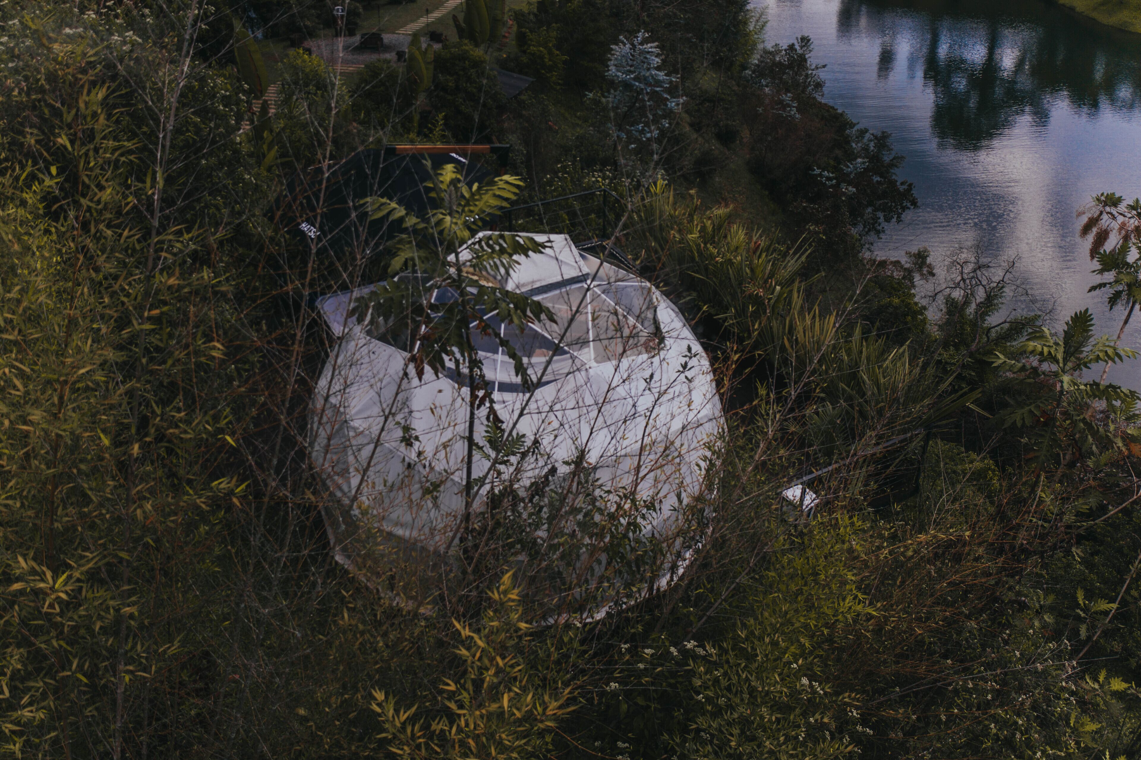 A dome-shaped structure surrounded by dense vegetation and a body of water.