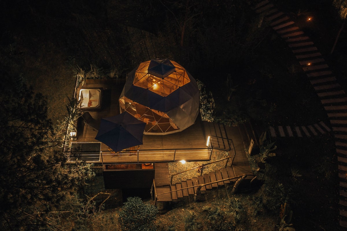 A spherical structure with a wooden deck and a staircase leading up to it.