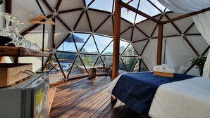 Ein Zelttraum mit Bett, Holzmöbeln und Blick ins Freie.