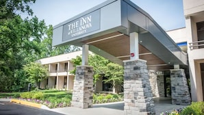 The Inn at Villanova University entrance with stone pillars, a covered walkway, and a landscaped garden. - Inn at Villanova University (Wayne)