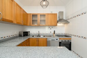 A kitchen with wooden cabinets, a microwave, a sink, a dishwasher, and a stove.