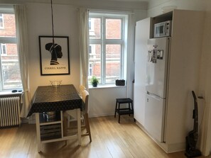 Compact kitchen with a dining area offering a city view, featuring a refrigerator, microwave, and sink.