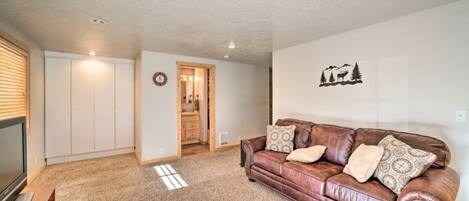 A living room with a brown leather couch, a television, and a closet.