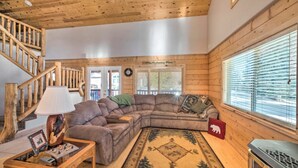 A cozy cabin interior with a wooden staircase, a sectional sofa, a small table with a lamp, and a fireplace. - Experience Yellowstone magic, just 27 mins away
A.C.  Sleeps 10+ (Island Park)