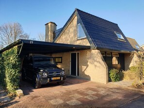 Ein zweistöckiges Haus mit Satteldach, einer Garage und einem schwarzen Auto auf der Auffahrt.