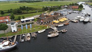 Un port de plaisance avec des bateaux amarrés, un restaurant doté d’une terrasse, et une petite structure en forme de tour.