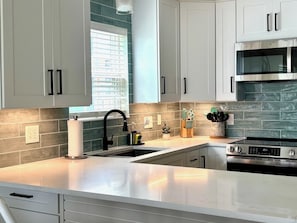 Una cocina moderna con armarios blancos, horno de acero inoxidable y microondas integrado.