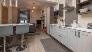 Een moderne keuken met een bar, witte kasten en roestvrijstalen apparatuur.