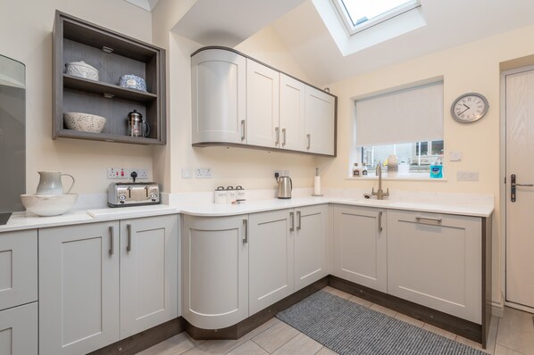 A modern kitchen with white cabinets, a built-in shelf, a toaster, and a coffee maker. - 4 Bedrooms, sleeping 6,  just 2 minutes walk from Hebden Bridge town square . (Hebden Bridge)