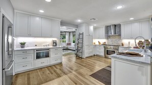 Una cocina moderna con armarios blancos, electrodomésticos de acero inoxidable y piso de madera.