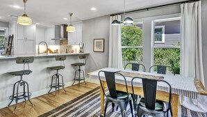 Una cocina moderna con armarios blancos, una isla de madera e iluminación colgante.