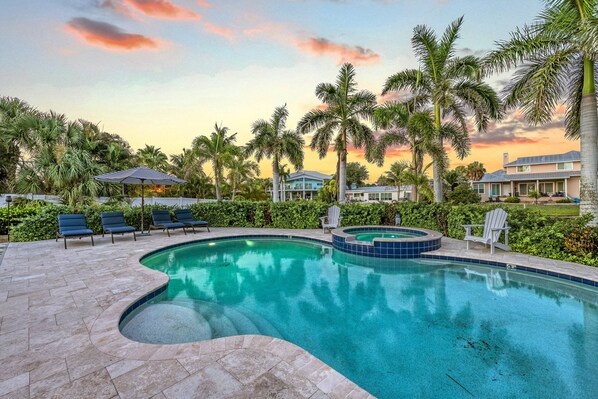 A swimming pool with a hot tub, surrounded by palm trees and lounge chairs. - Blu Sky Cottage | Waterfront Pool Home, Resort-Style Backyard, Near Siesta Key Village (Siesta Key)